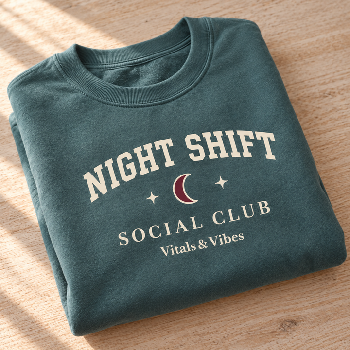 Night Shift crewneck in Blue Spruce, folded for a close detail view, showing the Night Shift moon, stars and Social Club print.