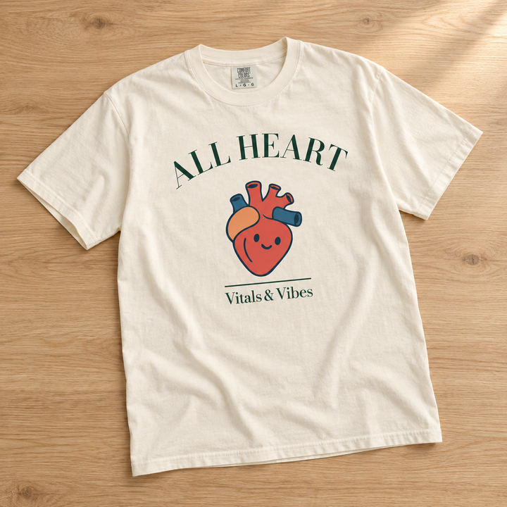 All Heart tee in Ivory, laid out on a table, showing the All Heart lettering and smiling anatomical heart design.