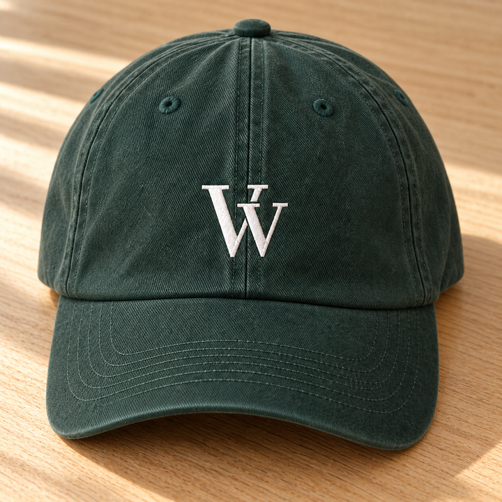 Close view of the Spruce Everyday Dad Cap on warm oak, showing the white VV embroidery, twill texture and curved-brim stitching.