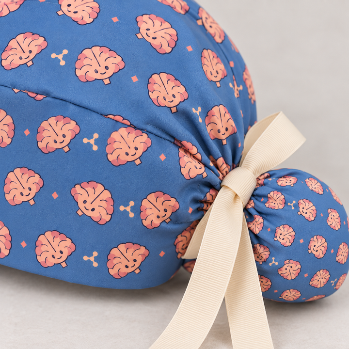 Brain ponytail scrub cap — close-up mockup showing the printed fabric and stitched seam.