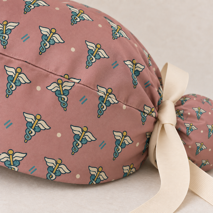 Caduceus ponytail scrub cap — close-up mockup showing the printed fabric and stitched seam.
