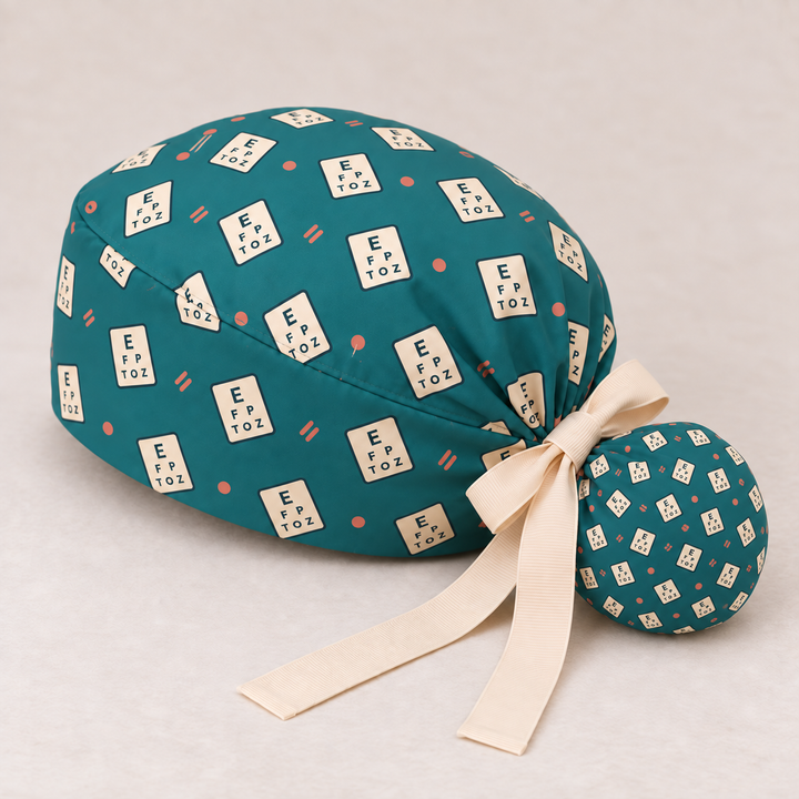 Eye Chart ponytail scrub cap — studio mockup showing the printed cap and cream ties.