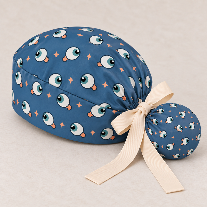 Eye ponytail scrub cap — studio mockup showing the printed cap and cream ties.