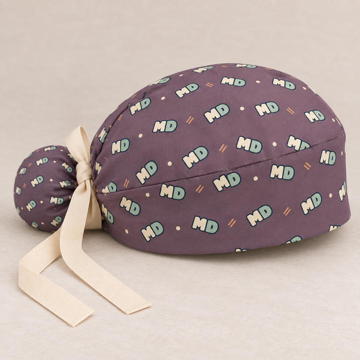 MD ponytail scrub cap — studio mockup showing the printed cap and cream ties.