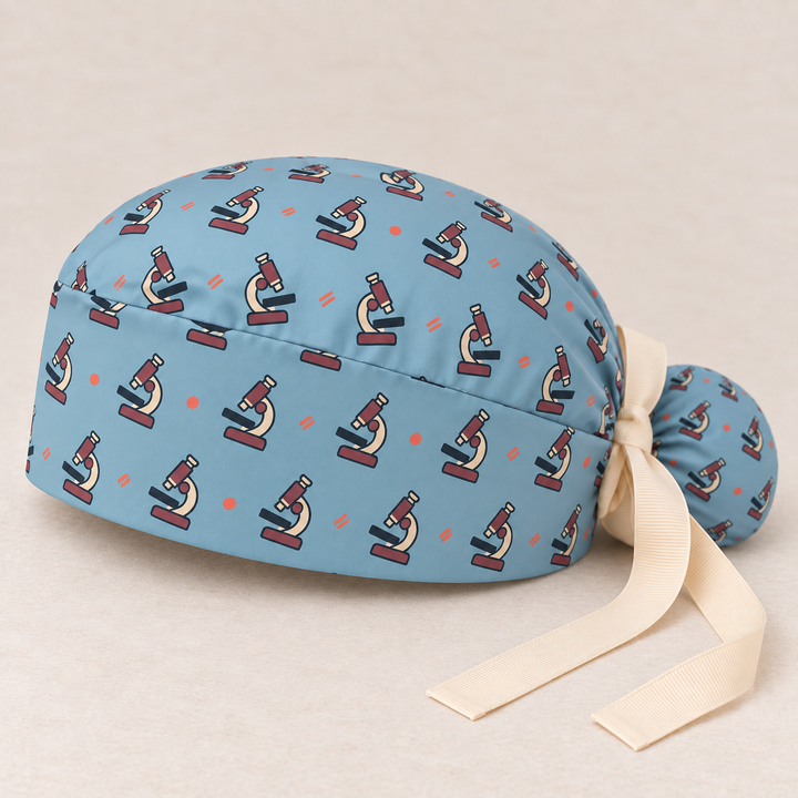 Microscope ponytail scrub cap — studio mockup showing the printed cap and cream ties.