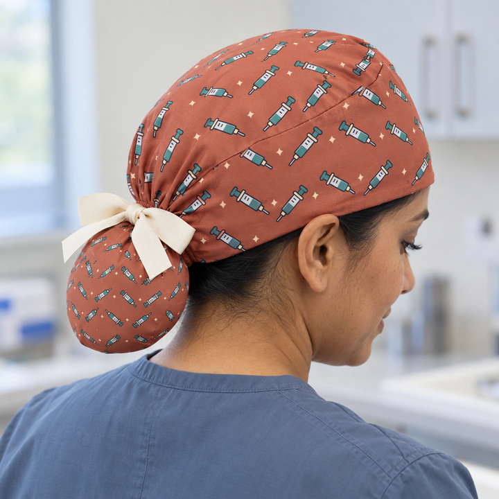 Needle ponytail scrub cap worn with plain scrubs in a clinical-setting mockup.
