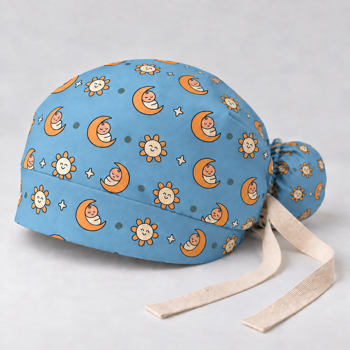 Pediatric ponytail scrub cap — studio mockup showing the printed cap and cream ties.