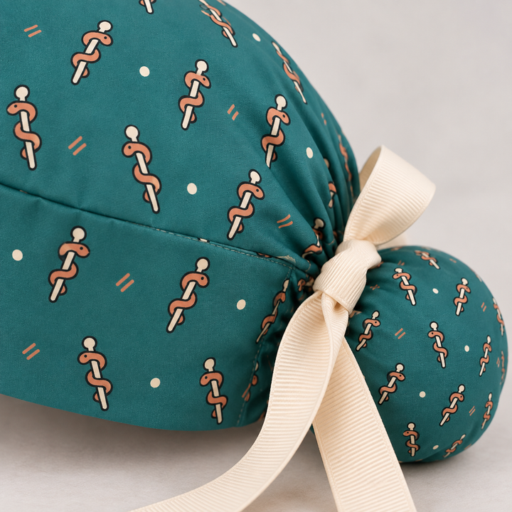 Rod of Asclepius ponytail scrub cap — close-up mockup showing the printed fabric and stitched seam.