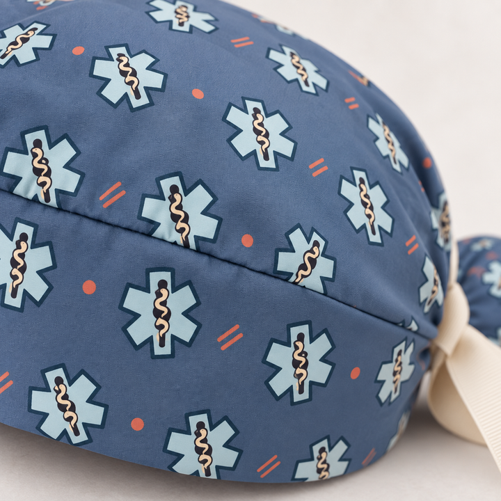 Star of Life ponytail scrub cap — close-up mockup showing the printed fabric and stitched seam.