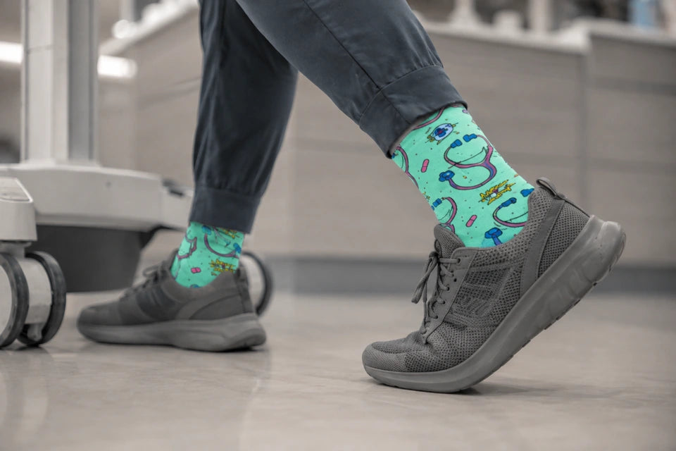 Colorful stethoscope socks and gray sneakers beside a workstation at a nursing station.